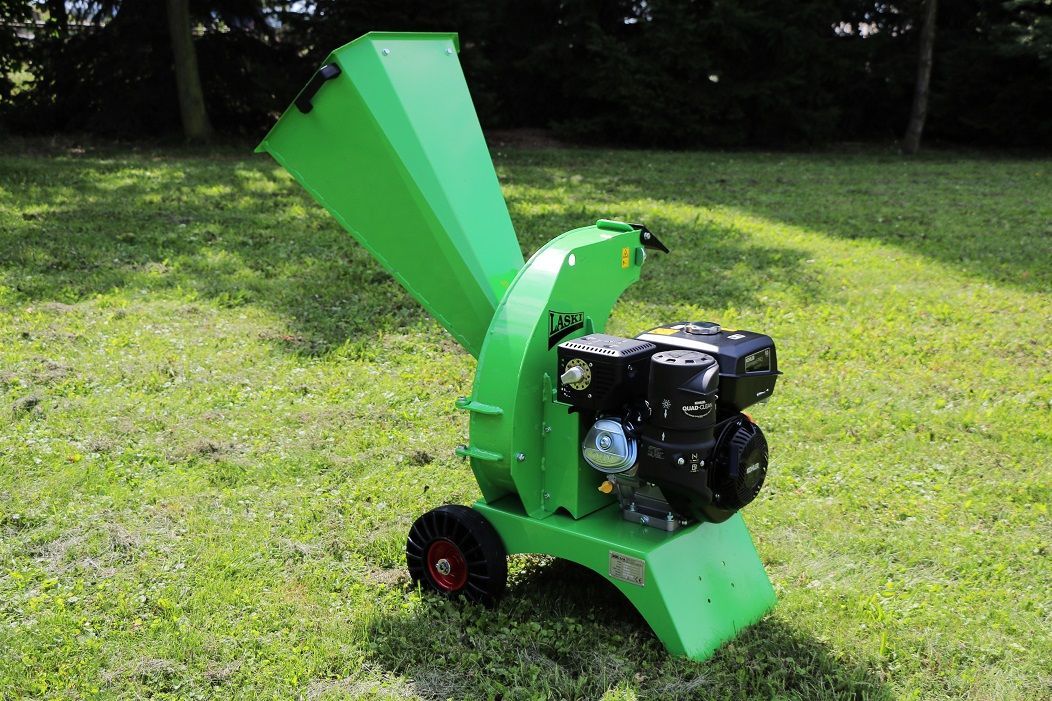 Auf einem üppigen grünen Rasen steht ein grüner Baumhäcksler.