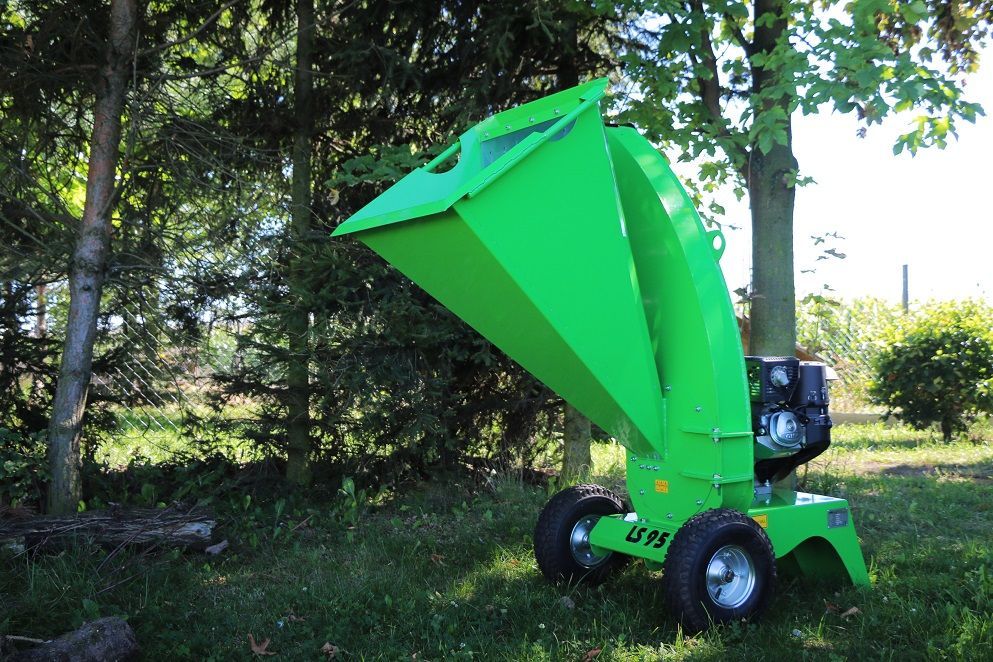 Eine grüne Maschine steht im Gras neben einem Baum.