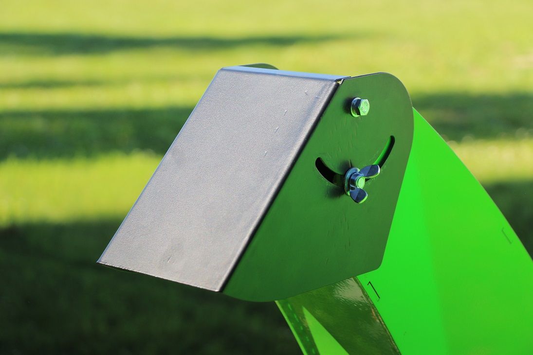 Eine Nahaufnahme eines grünen Eimers auf einem Traktor auf einem Feld.