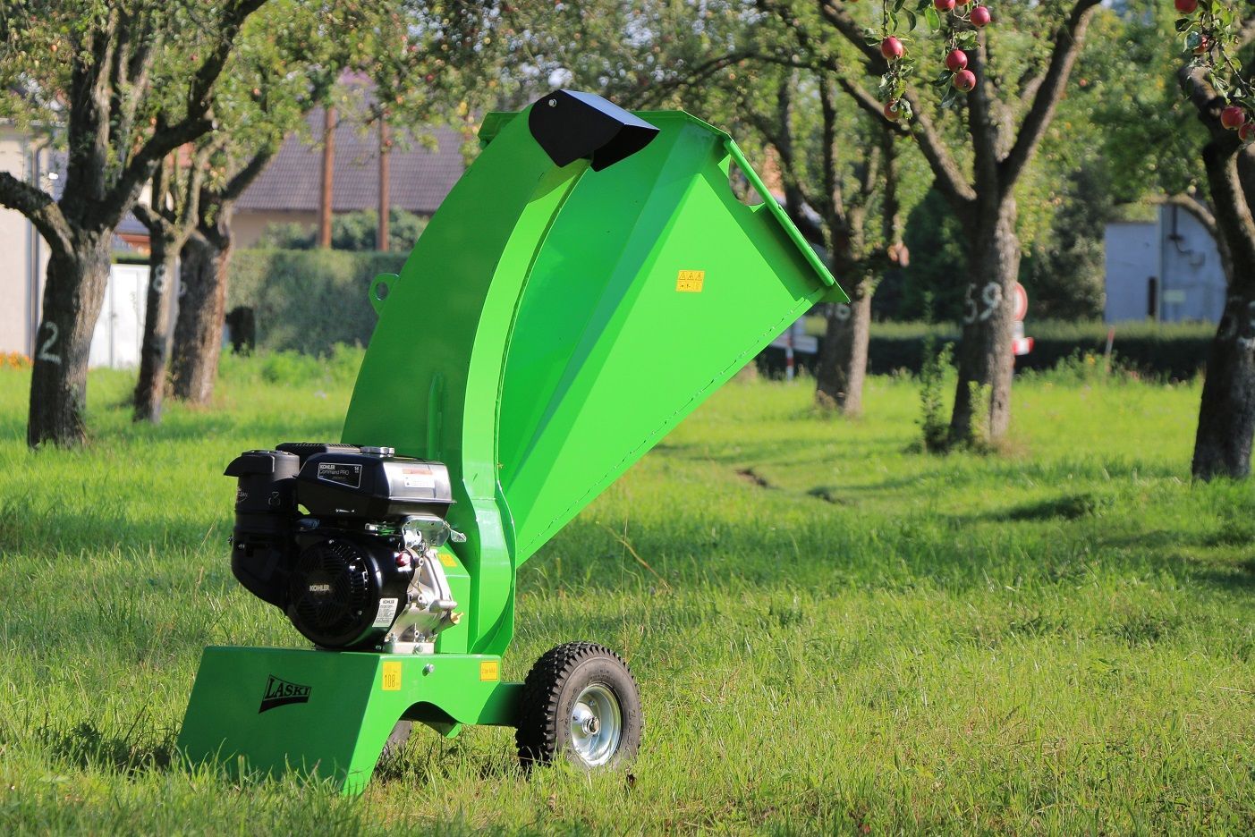 Ein grüner Häcksler steht mitten auf einer Wiese.