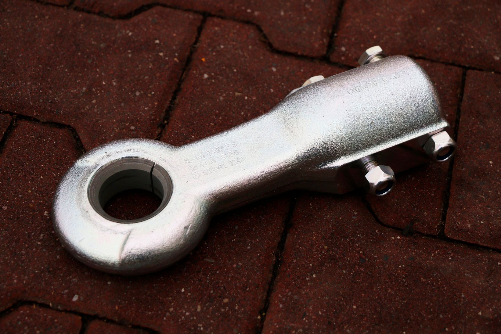 Ein Metallgegenstand mit einem Loch in der Mitte liegt auf einem Ziegelboden.