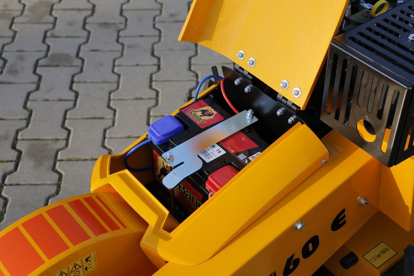 Ein gelbes Fahrzeug mit geöffneter Motorhaube hat hinten eine Batterie