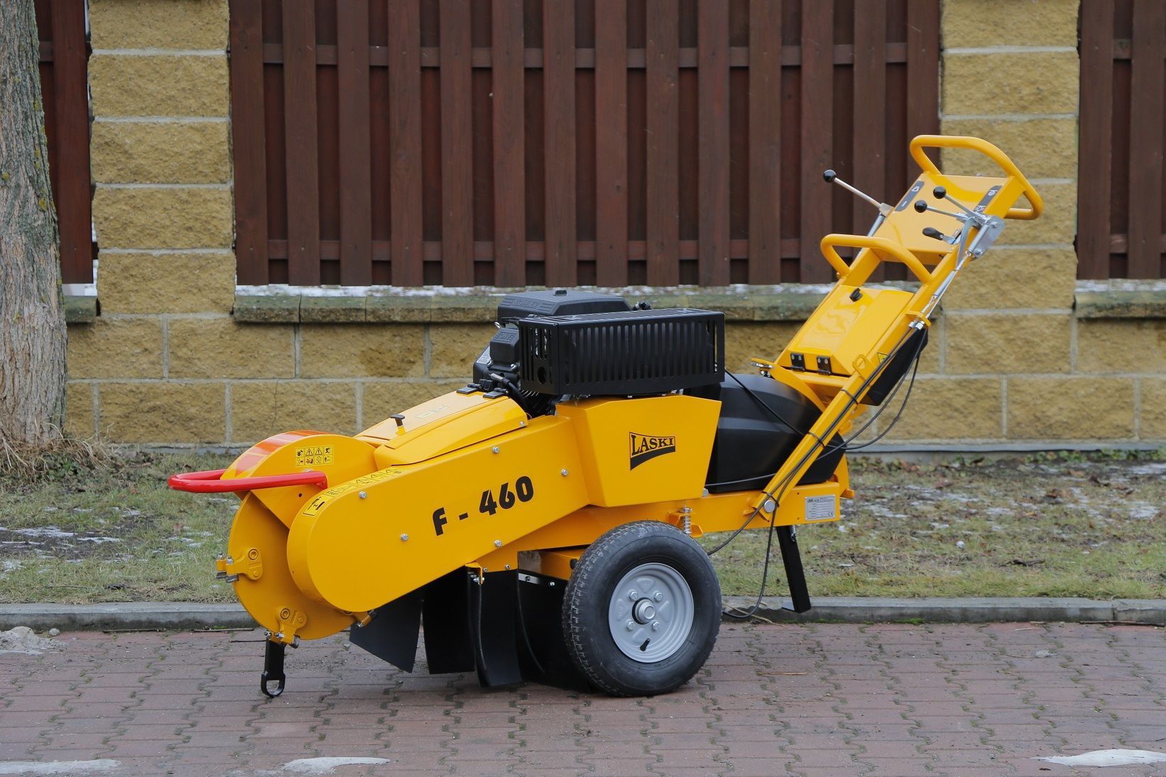 Eine gelbe Maschine steht am Straßenrand vor einem Zaun.