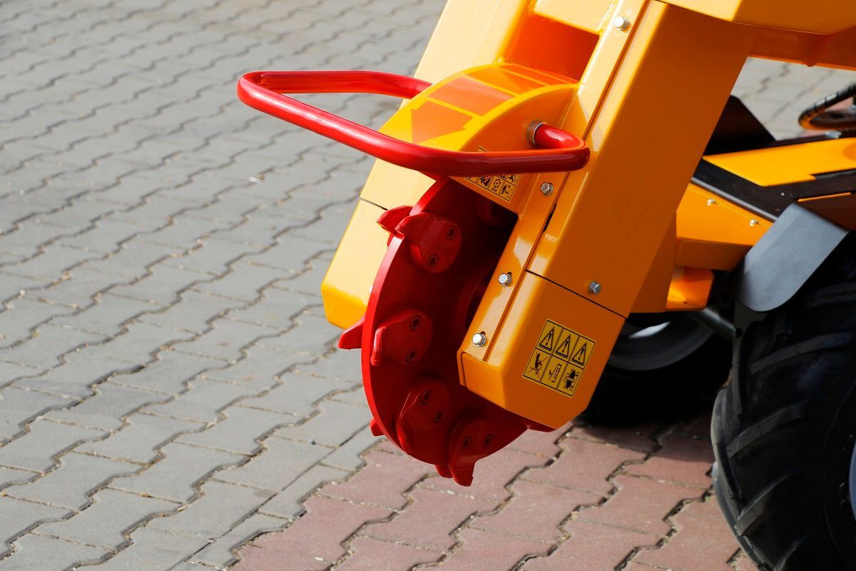 Ein gelber Traktor steht auf einem gepflasterten Gehweg