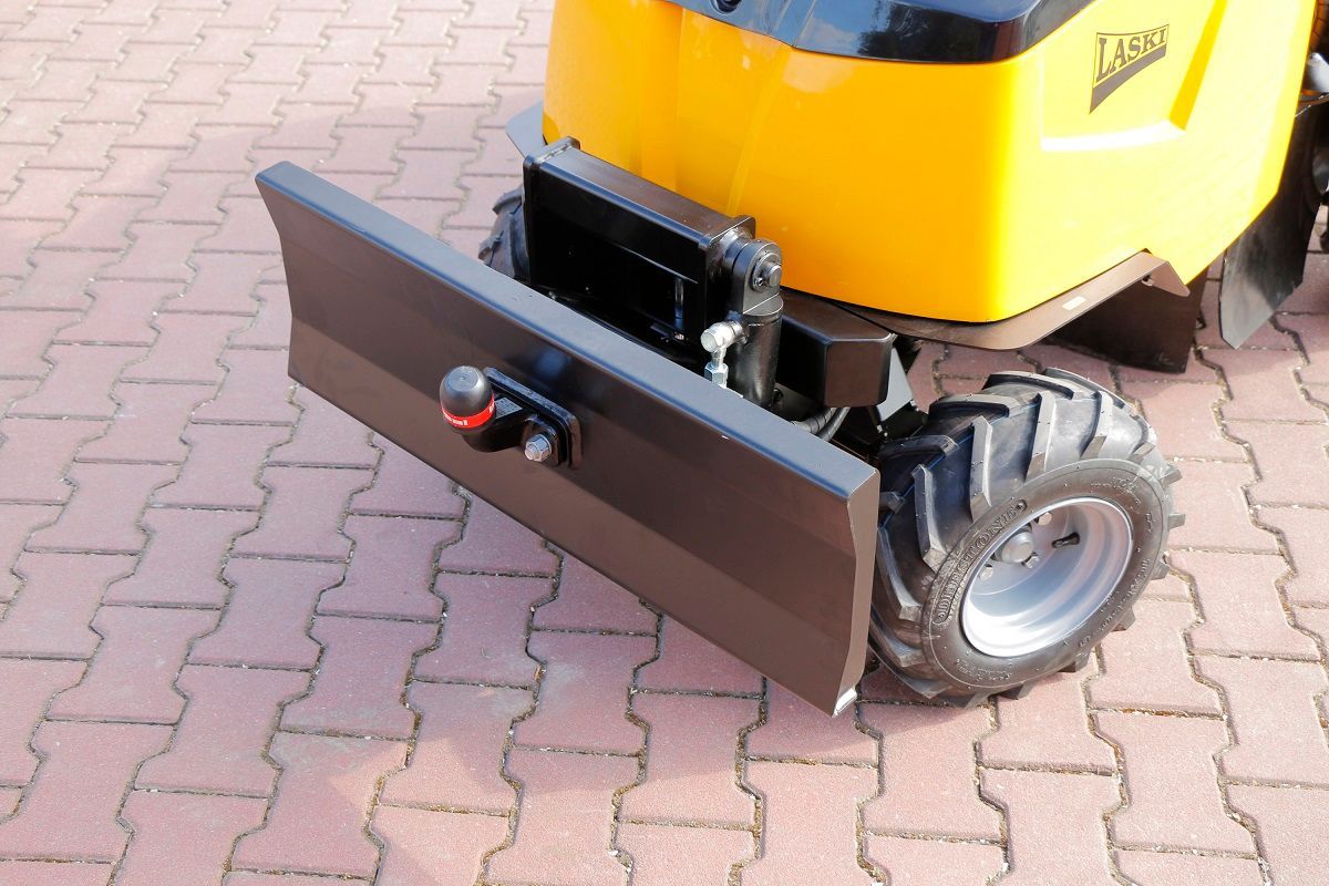 Ein gelber Traktor steht auf einem gepflasterten Gehweg