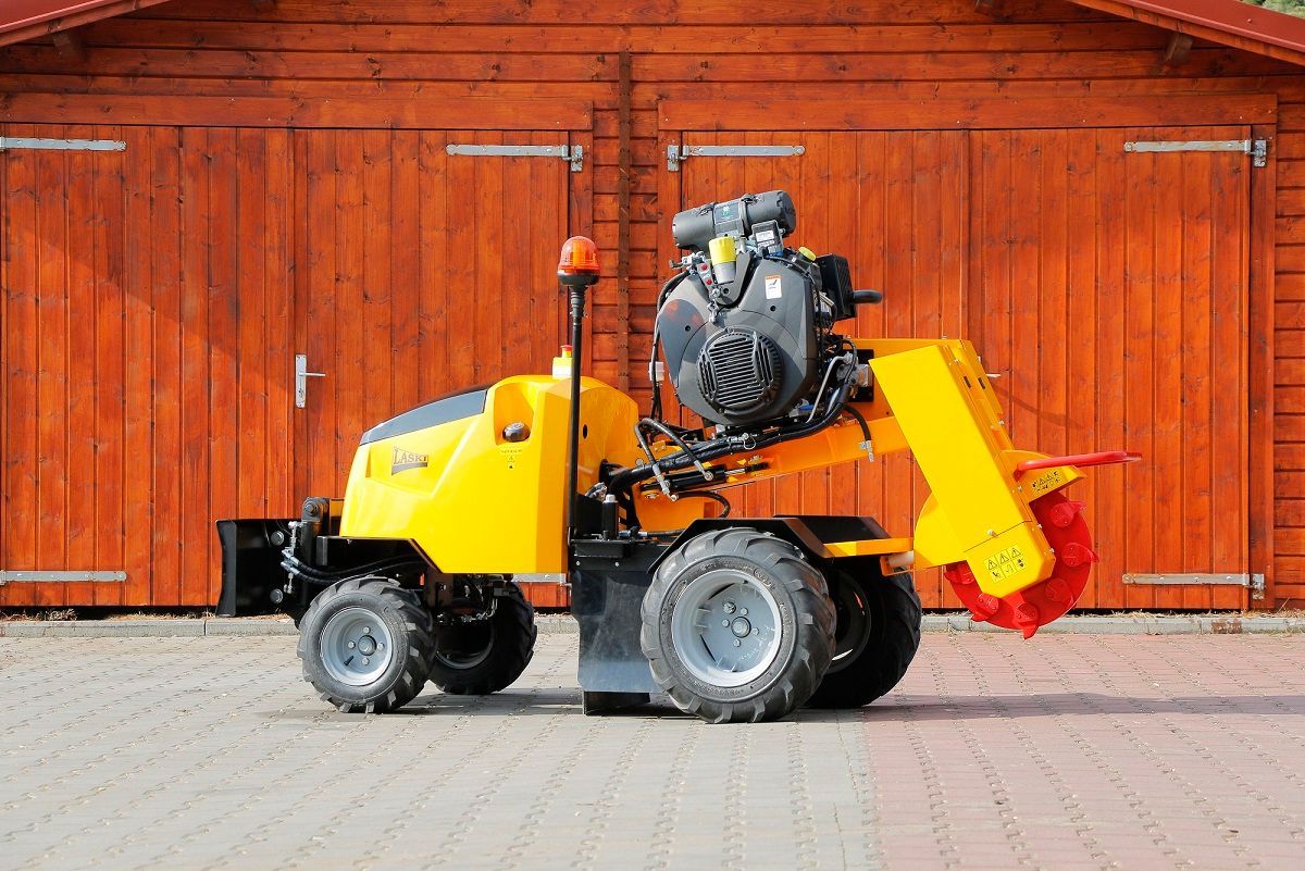 Ein gelber Traktor steht vor einer Holzgarage.