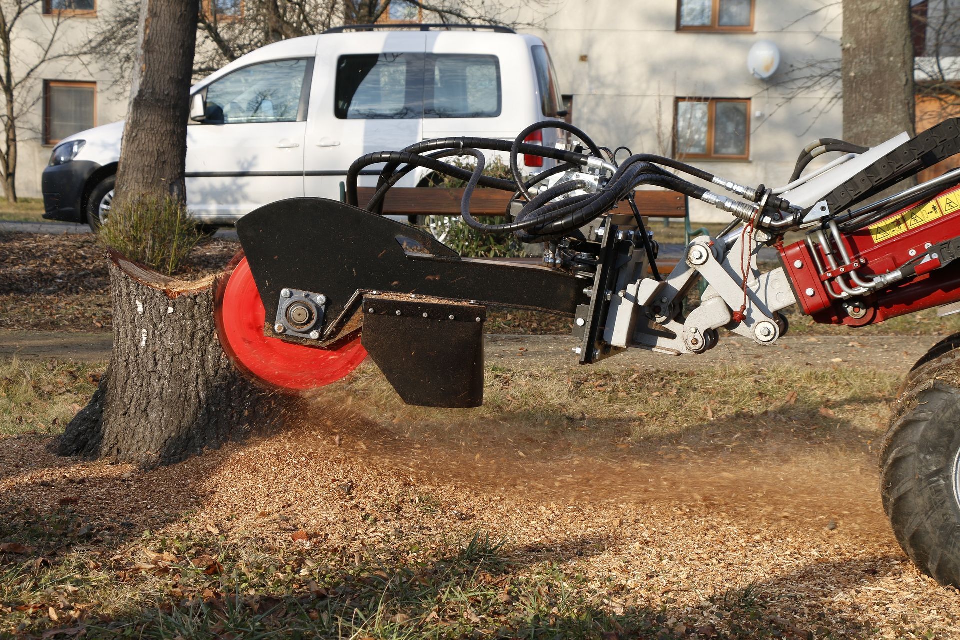 Eine Maschine fräst in einem Park einen Baumstumpf.