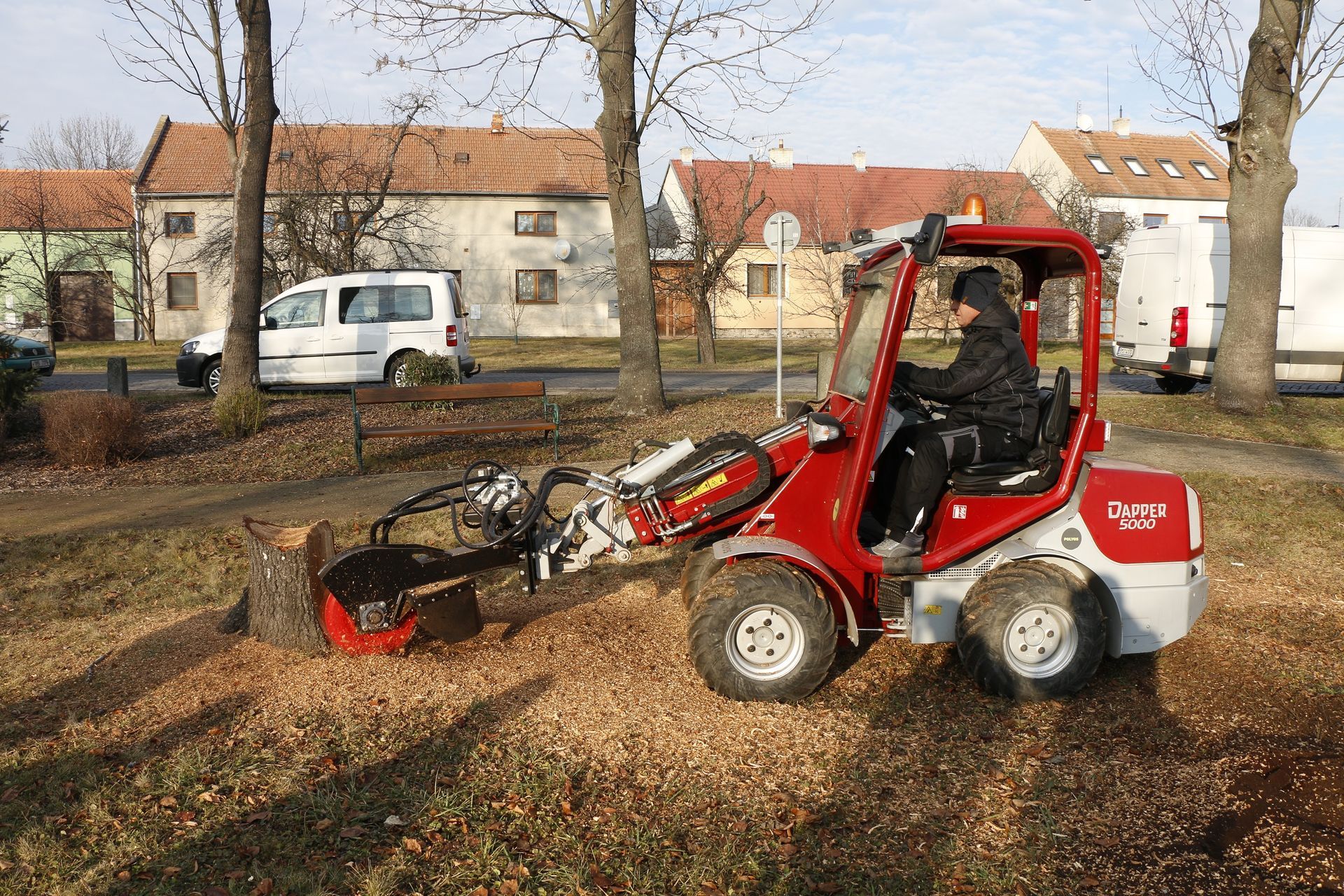 Ein Mann fährt einen rot-weißen Traktor durch einen Park.