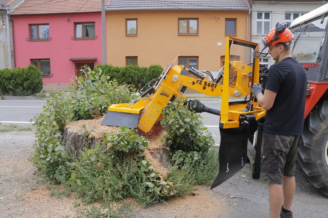 Ein Mann entfernt mit einer Maschine einen Baumstumpf.