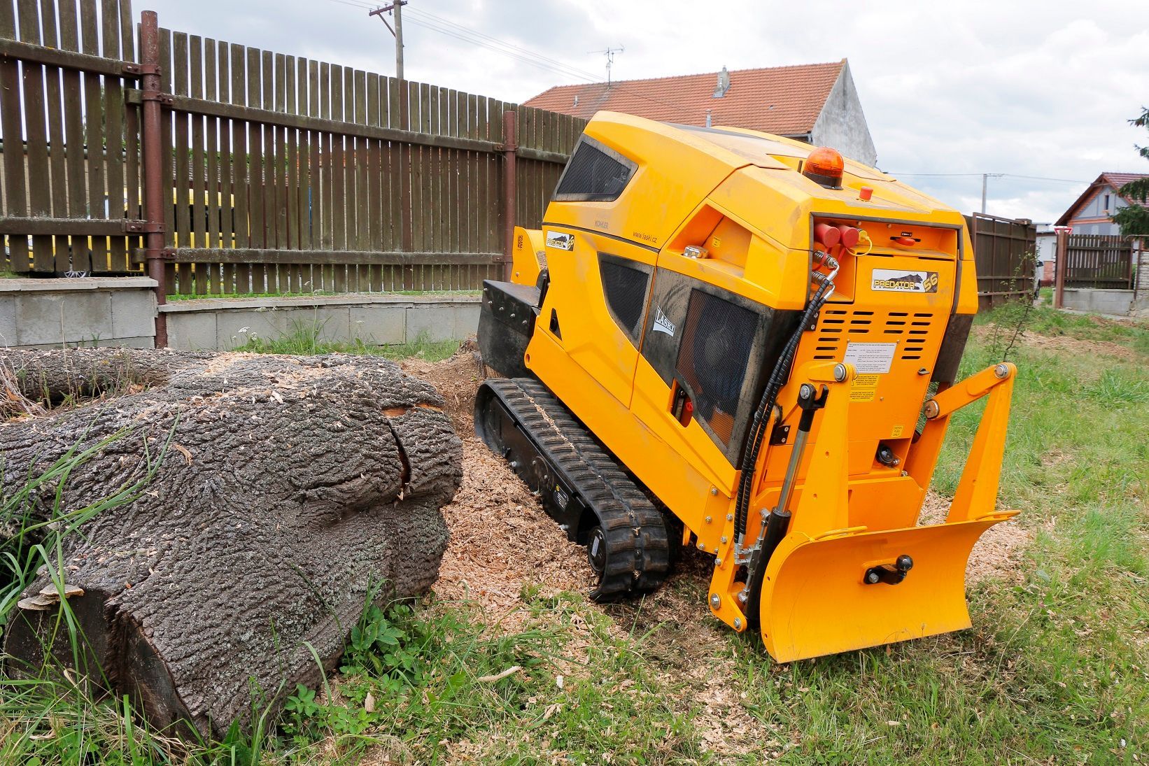 Ein gelber Traktor steht im Gras neben einem großen Felsen.