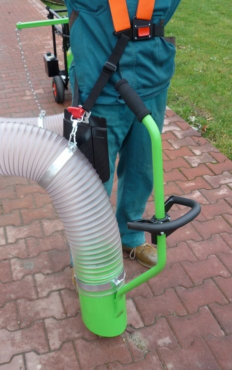 Eine Person steht auf einem Bürgersteig und ist mit einem grünen Schlauch verbunden