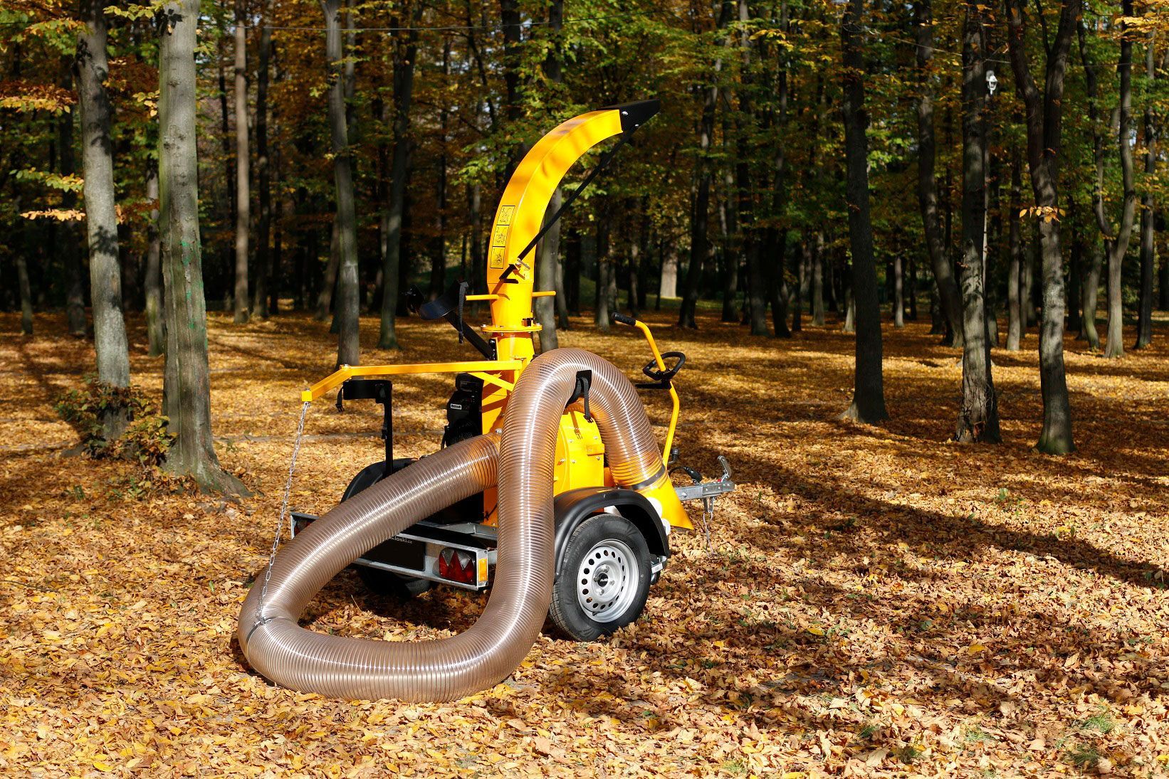 Ein gelber Laubsauger steht mitten im Wald.