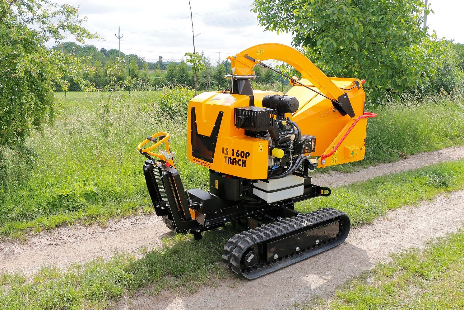 Eine kleine gelbe Maschine steht am Rand einer unbefestigten Straße.