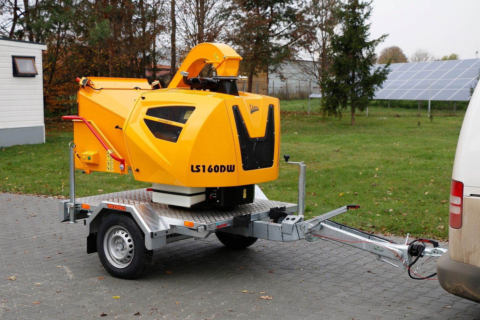 Eine gelbe Maschine steht auf einem Anhänger, der an einen Lieferwagen angehängt ist