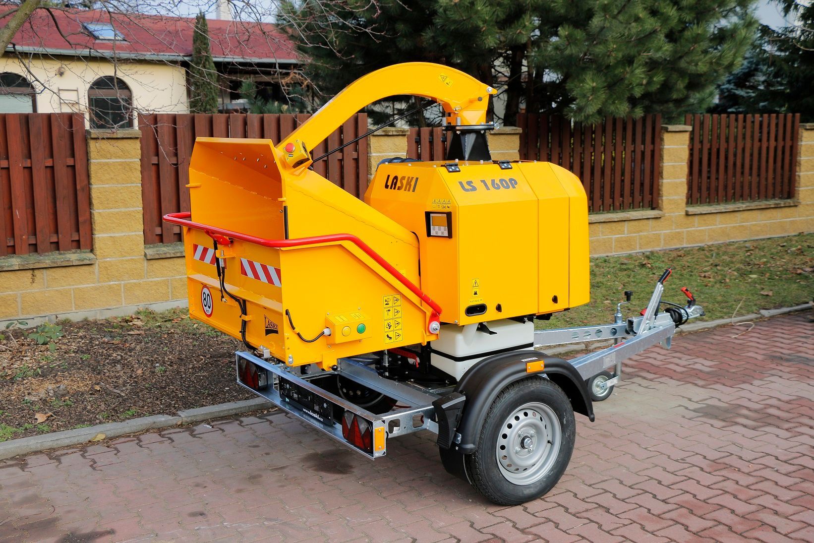 Eine gelbe Maschine auf einem Anhänger steht am Straßenrand.