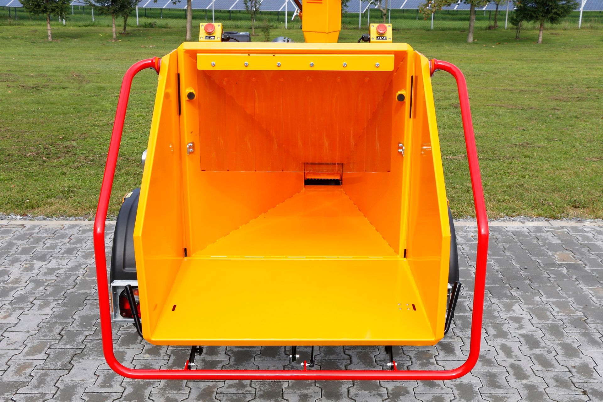 Eine gelb-rote Maschine ist auf einem gepflasterten Gehweg geparkt.