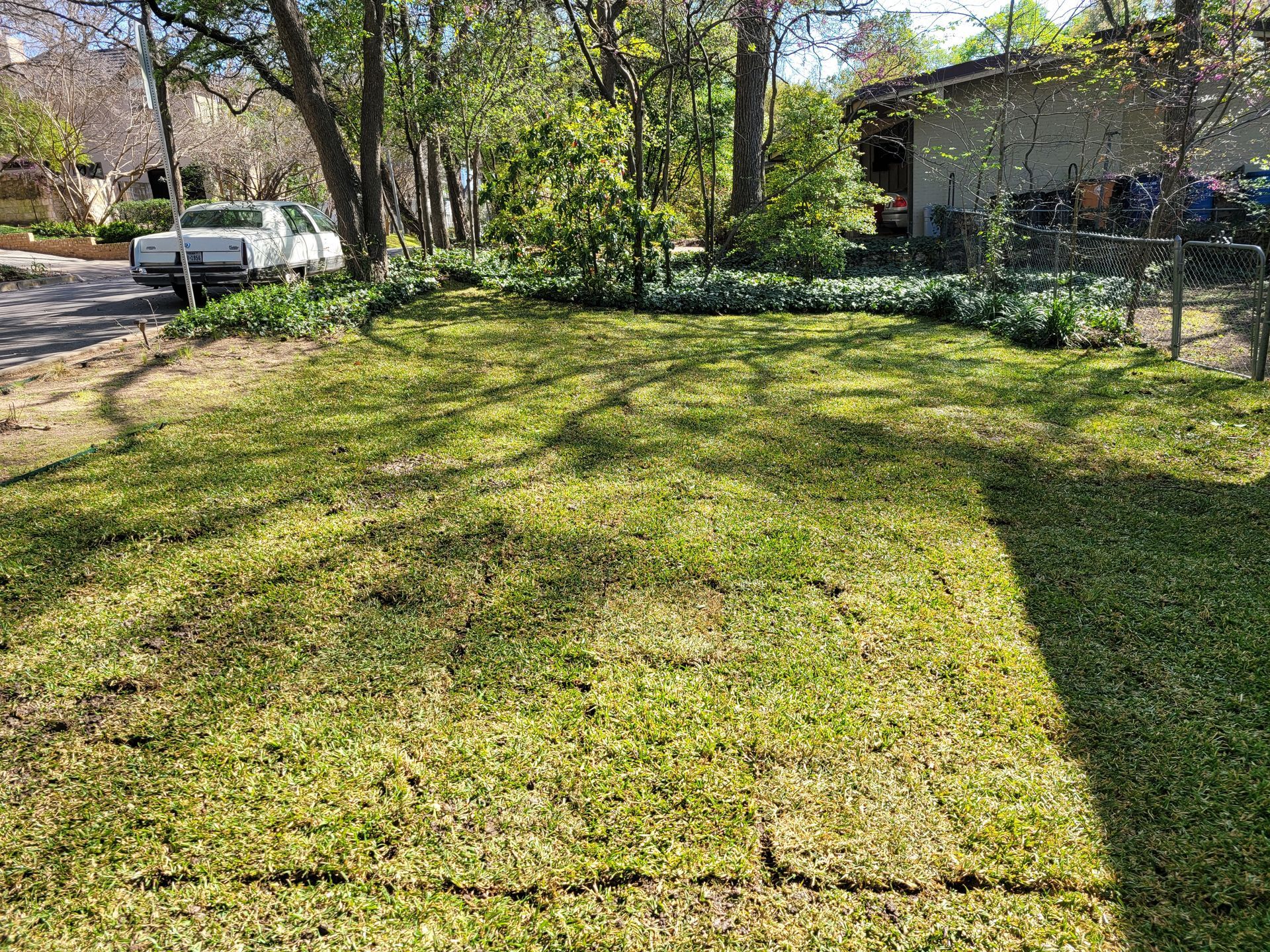 A white truck is parked in the grass in front of a house.