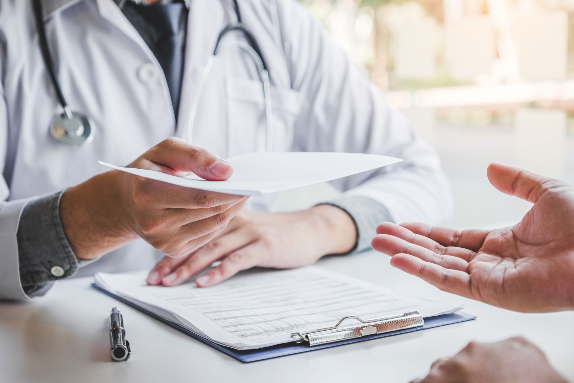 Doctor handing paperwork to patient during a consultation at a desk