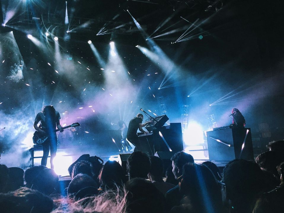 A group of people are standing in front of a stage at a concert.