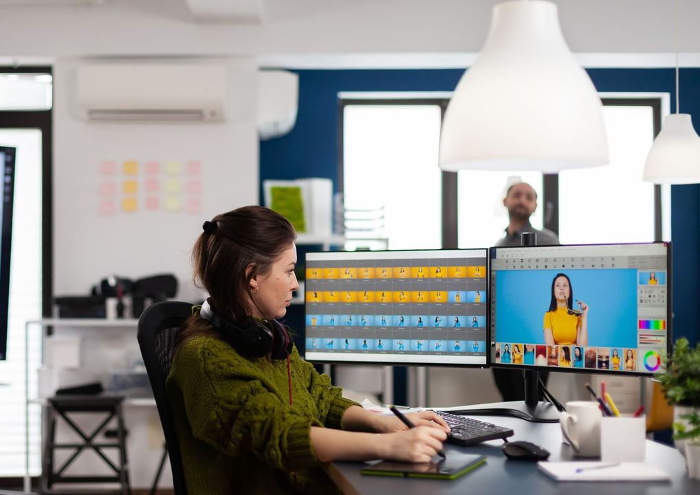 A woman is sitting at a desk in front of a computer.