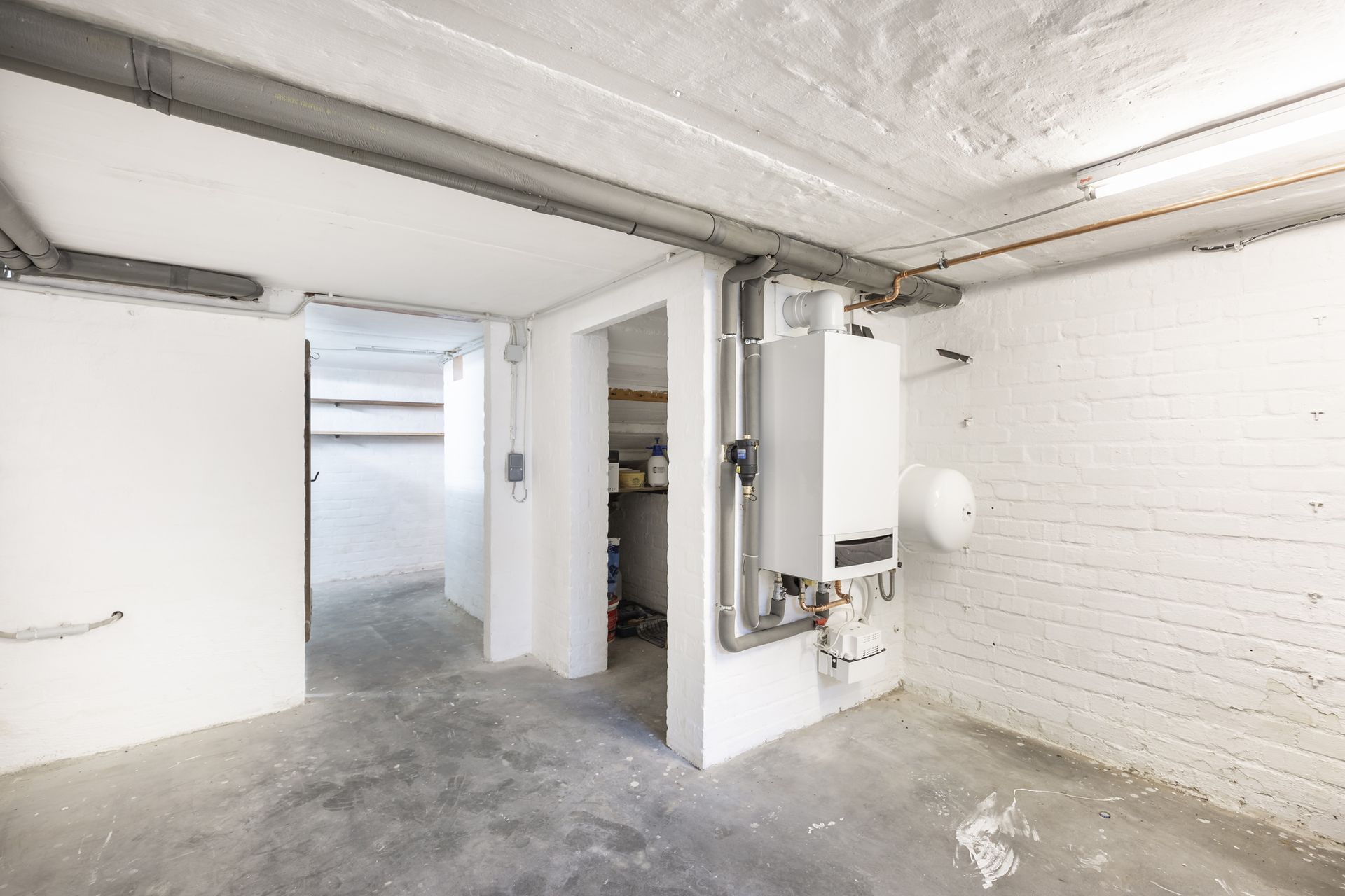 Basement with a white water heater on a brick wall and a doorway.