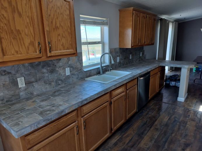 A kitchen with wooden cabinets , a sink , and a dishwasher.