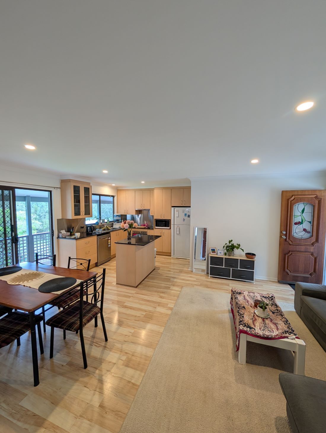 A Living Room With a Table and Chairs and a Kitchen in the Background — AitkenTech in Moruya, NSW