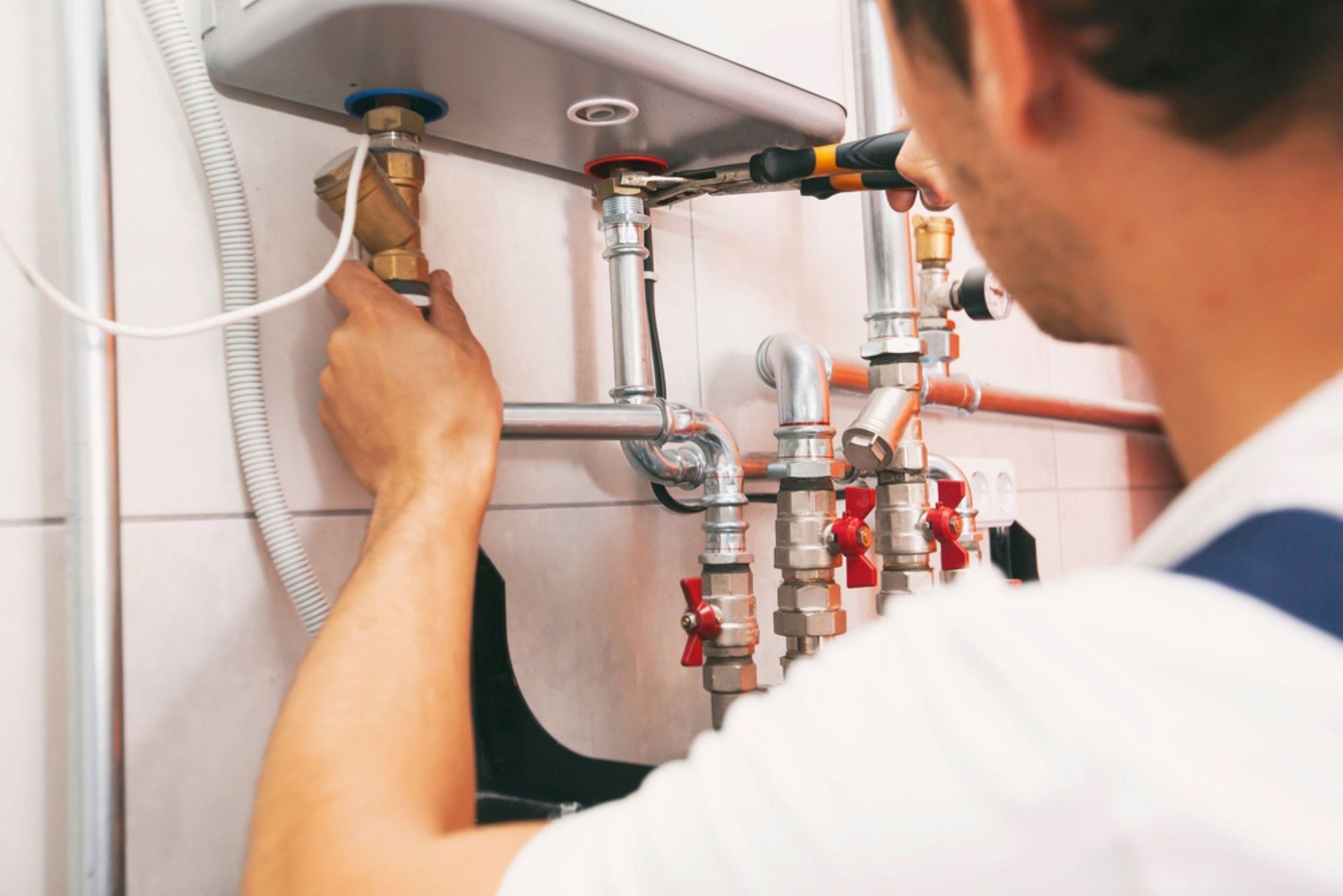 A Man is Fixing a Water Heater in a Bathroom — AitkenTech in Moruya, NSW