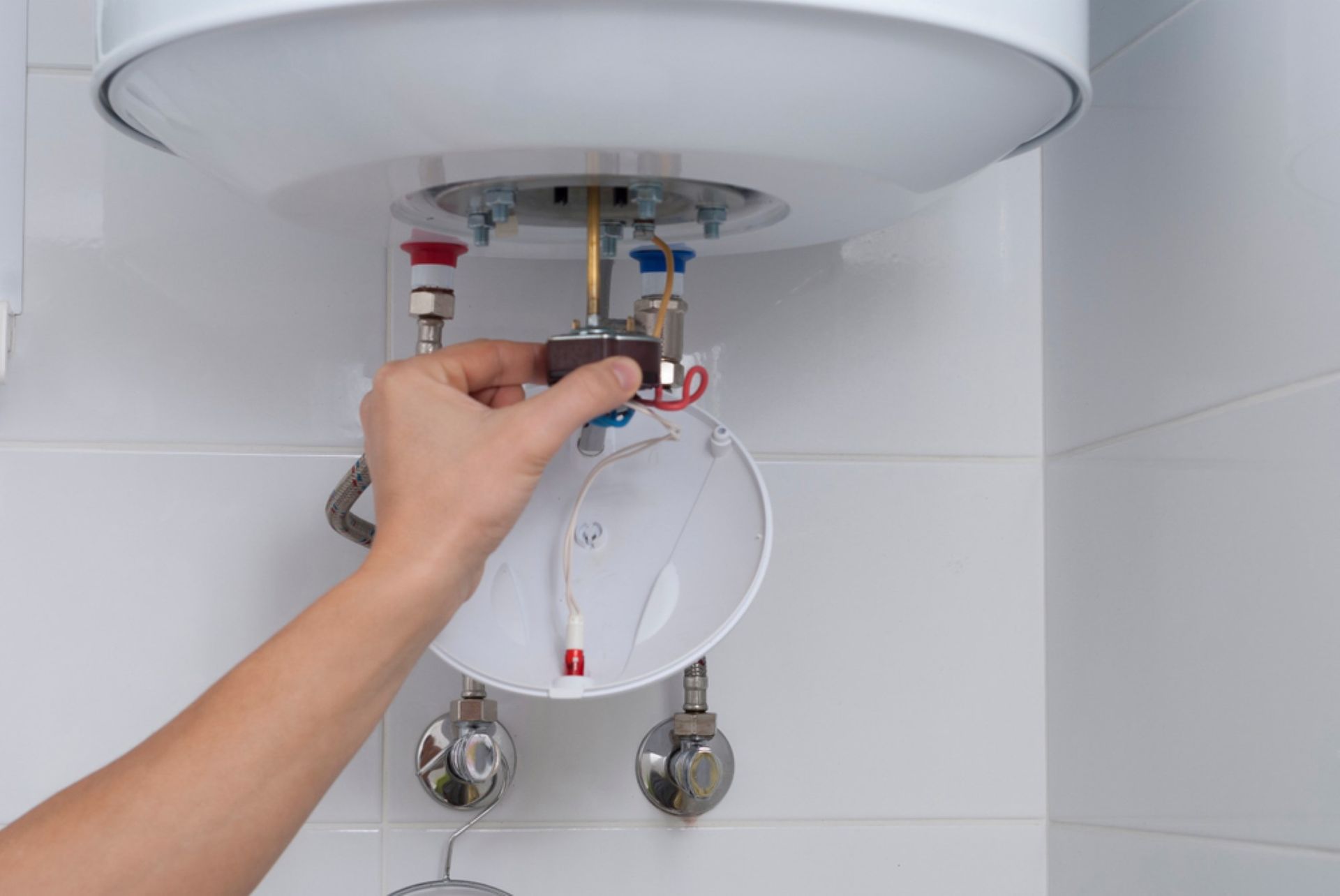 A Person is Fixing a Water Heater in a Bathroom — AitkenTech in Moruya, NSW
