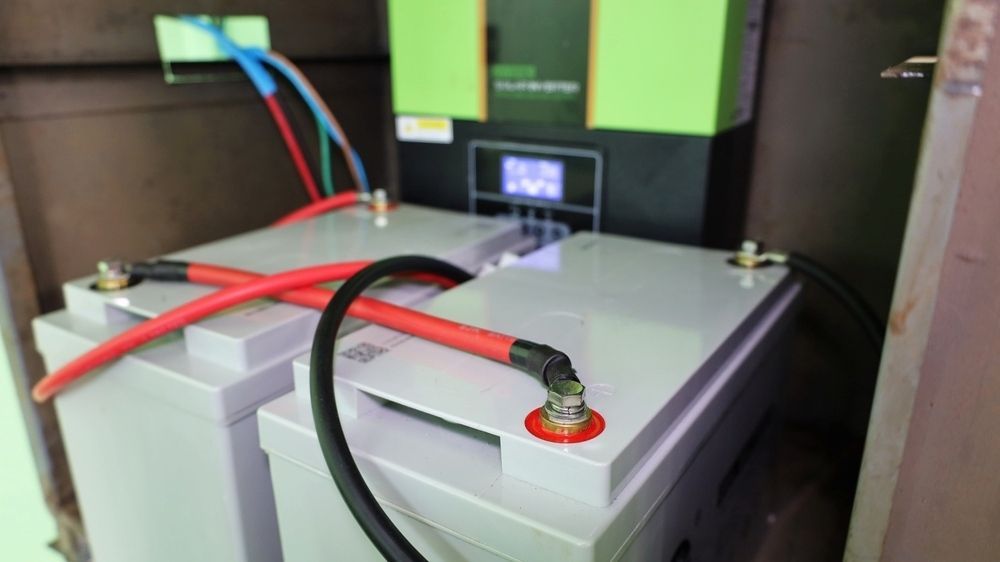 Two Batteries Connected With Cables and Green Device — AitkenTech inBermagui, NSW