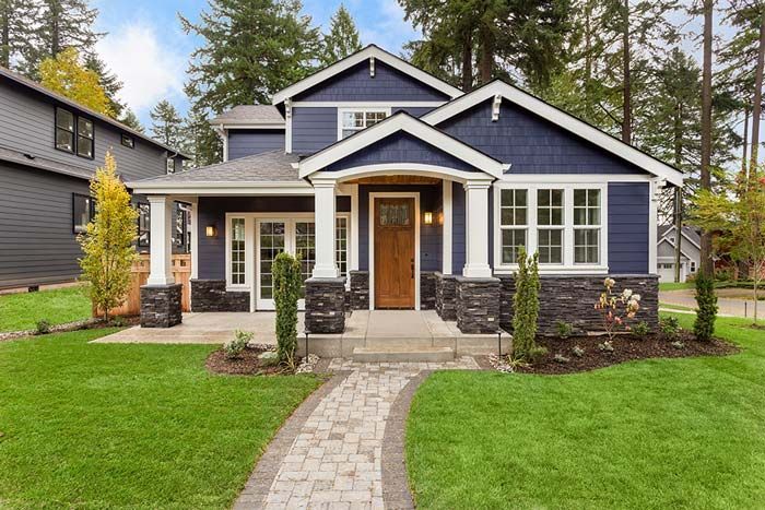 A blue house with a walkway leading to it and a lush green lawn.