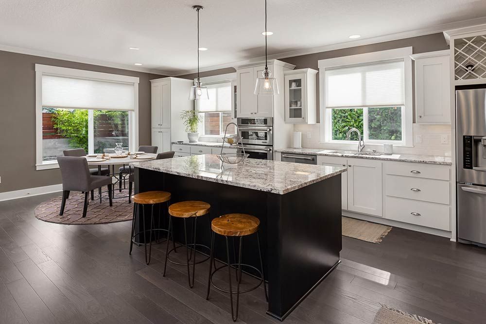 A kitchen with white cabinets , granite counter tops , stainless steel appliances and a large island.
