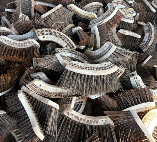 Pile of brown and white curved wire brushes stacked together
