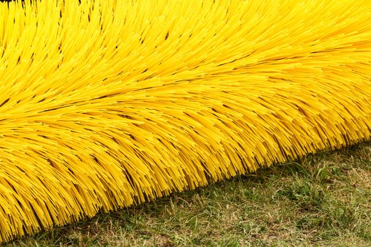 Bright yellow brush bristles resting on grass