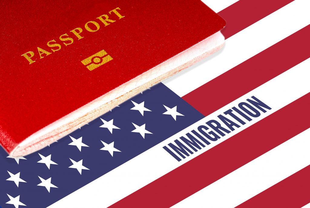 A red passport rests on the corner of a United States flag with the word 