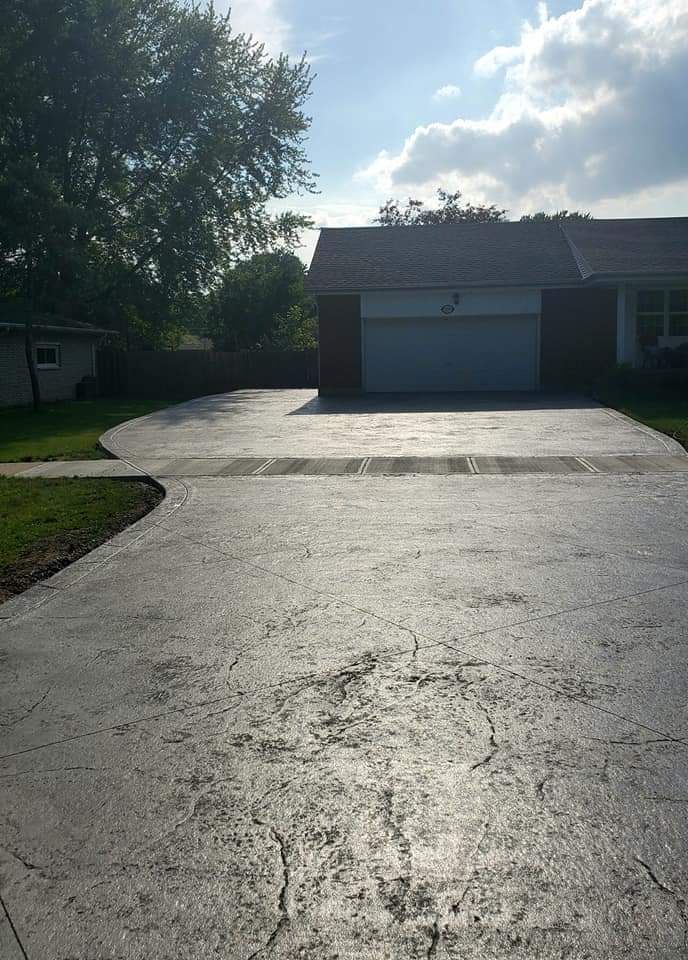 A concrete driveway leads to a house with a two-car garage under a sunny sky.