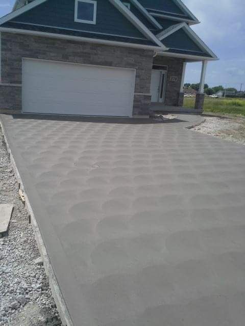 New concrete driveway leading to a house with a gray garage door.