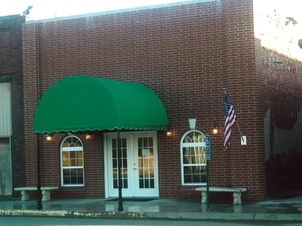 A brick building with a green awning and an american flag