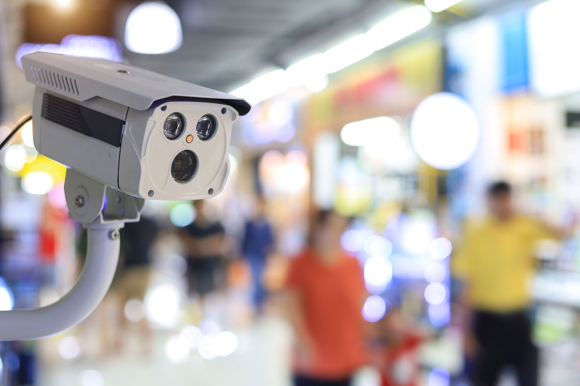 A security camera is sitting in front of a crowd of people in a shopping mall.