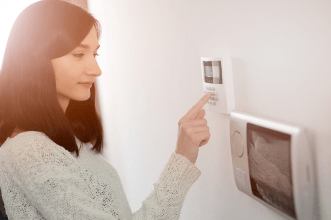A woman is pressing a button on a security system.