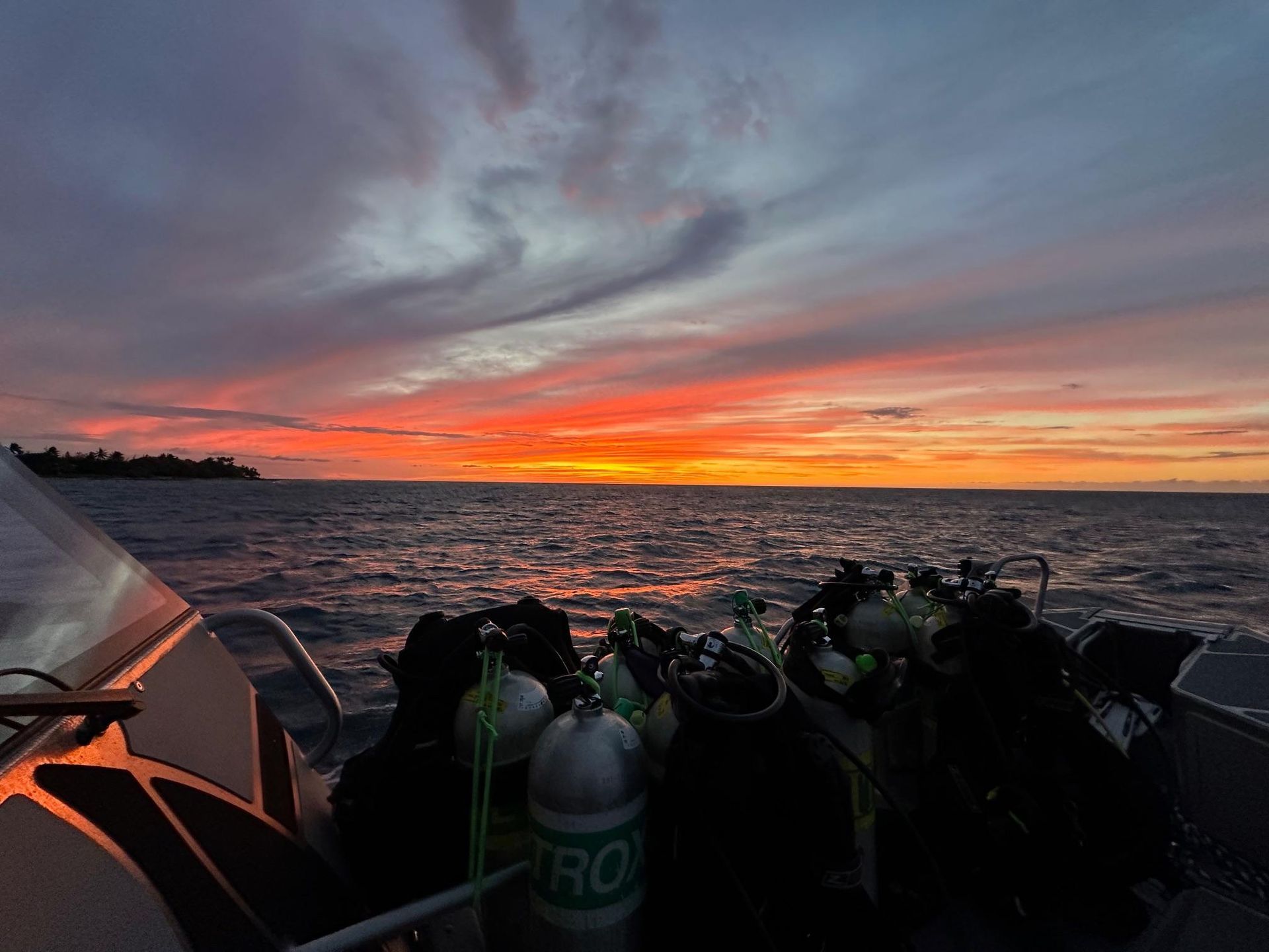 A sunset over the ocean with a boat in the foreground