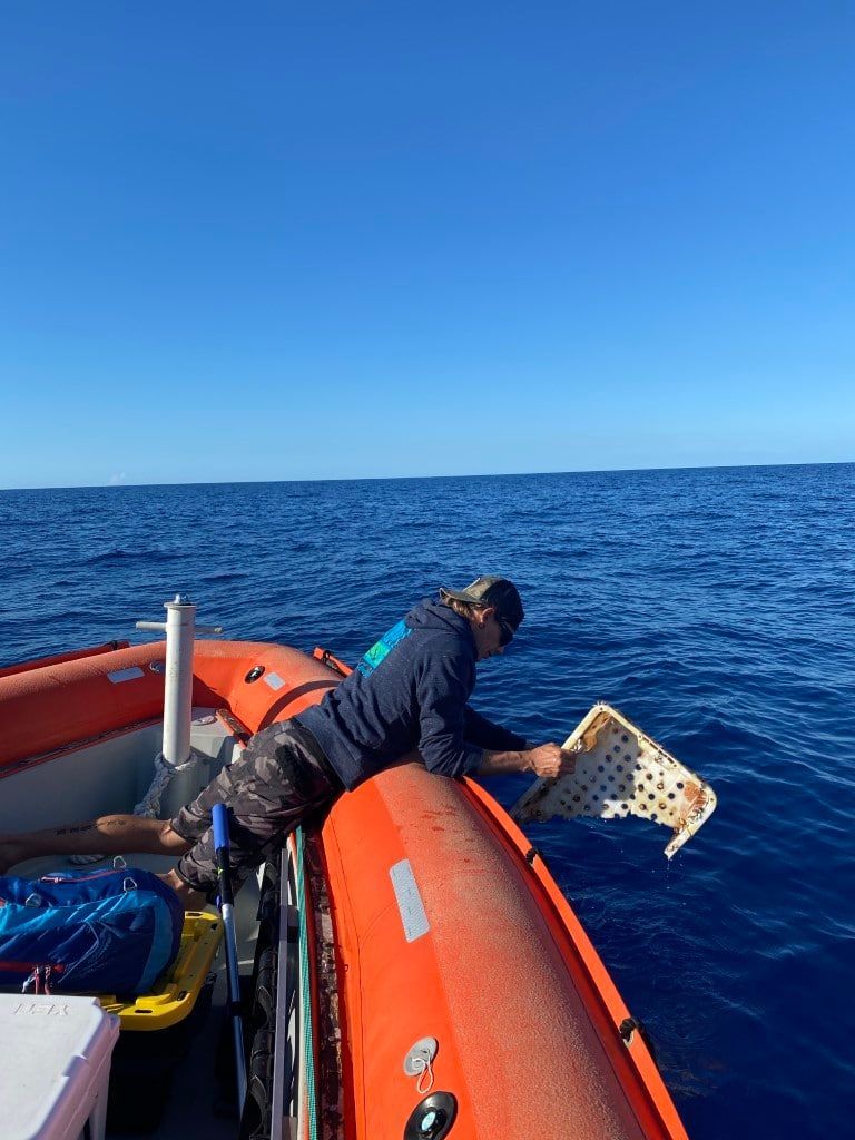 a man is laying on the back of an orange boat in the ocean