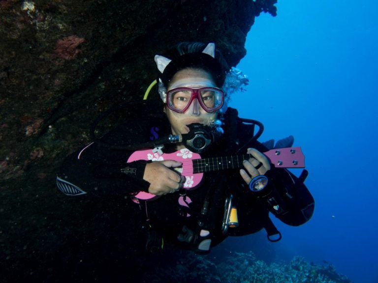 a scuba diver is playing a pink guitar underwater