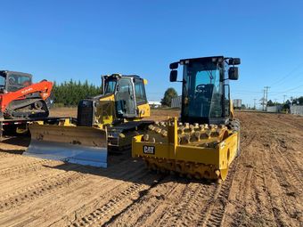 A yellow excavator is digging a hole in the woods.