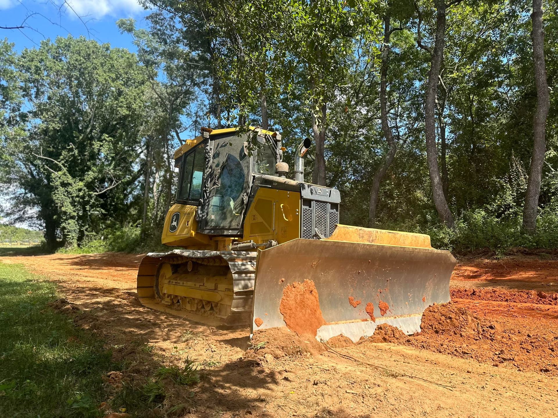 A bulldozer is moving dirt on a dirt road.