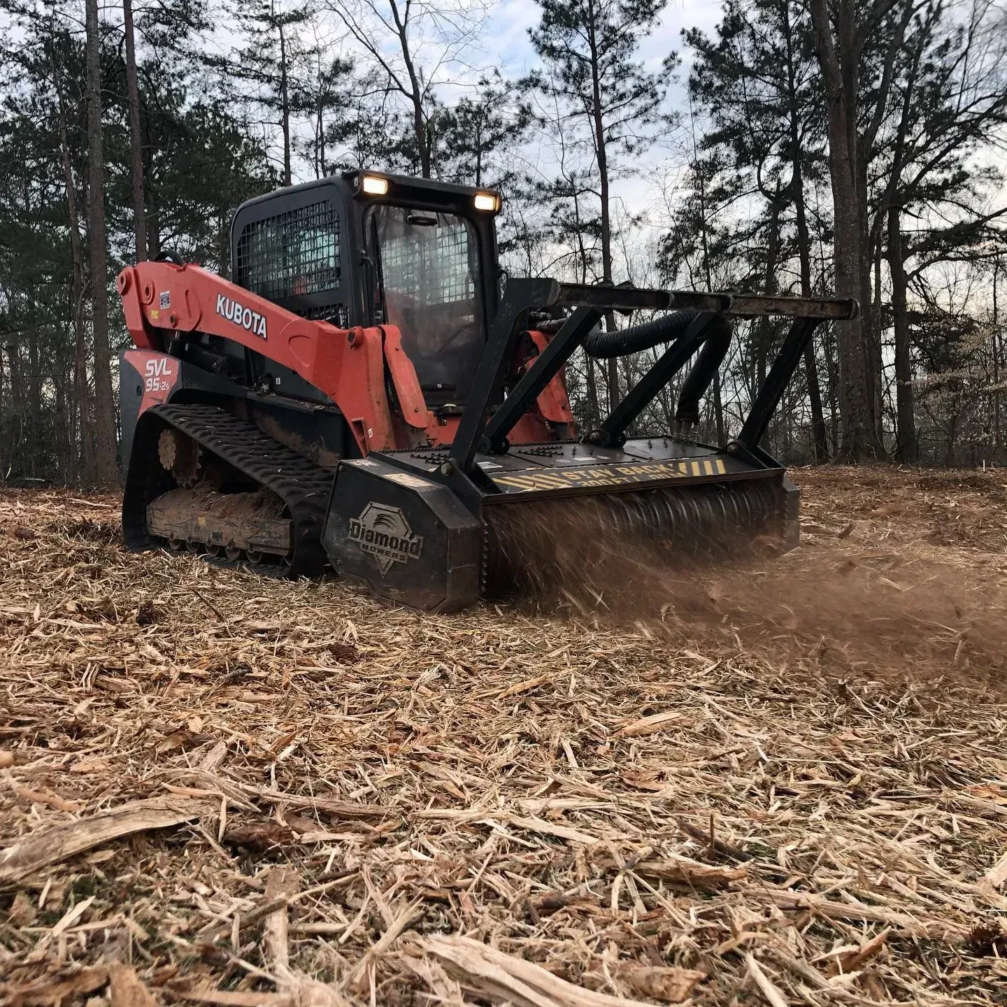 A bulldozer is driving through a field of wood chips.