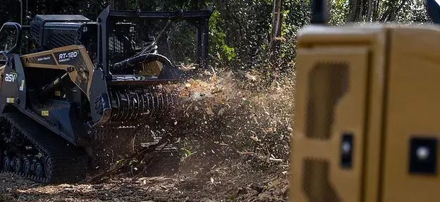 A bulldozer is cutting down trees in the woods.