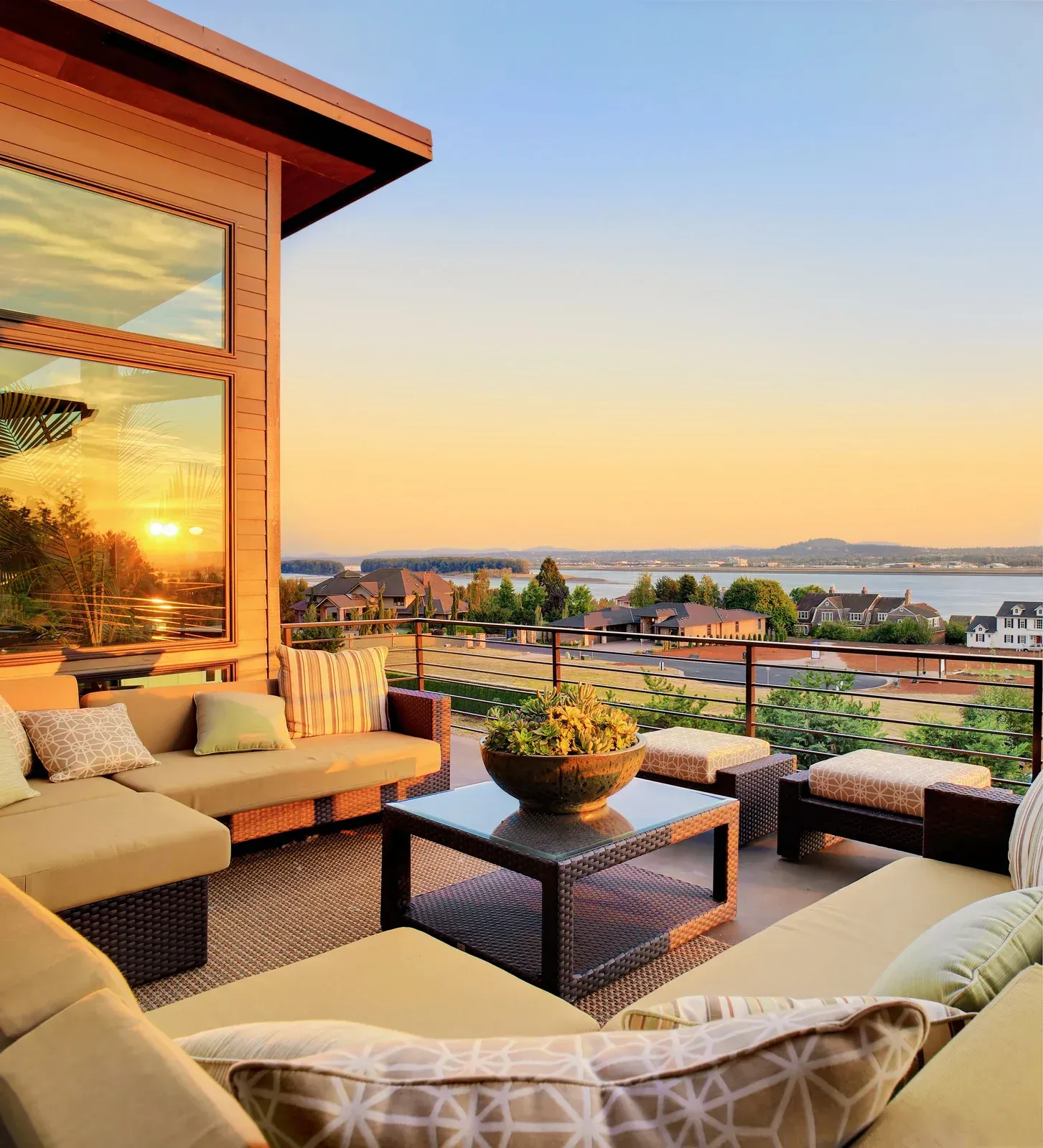 Outdoor patio with sectional sofa, coffee table, and sunset view over the water.