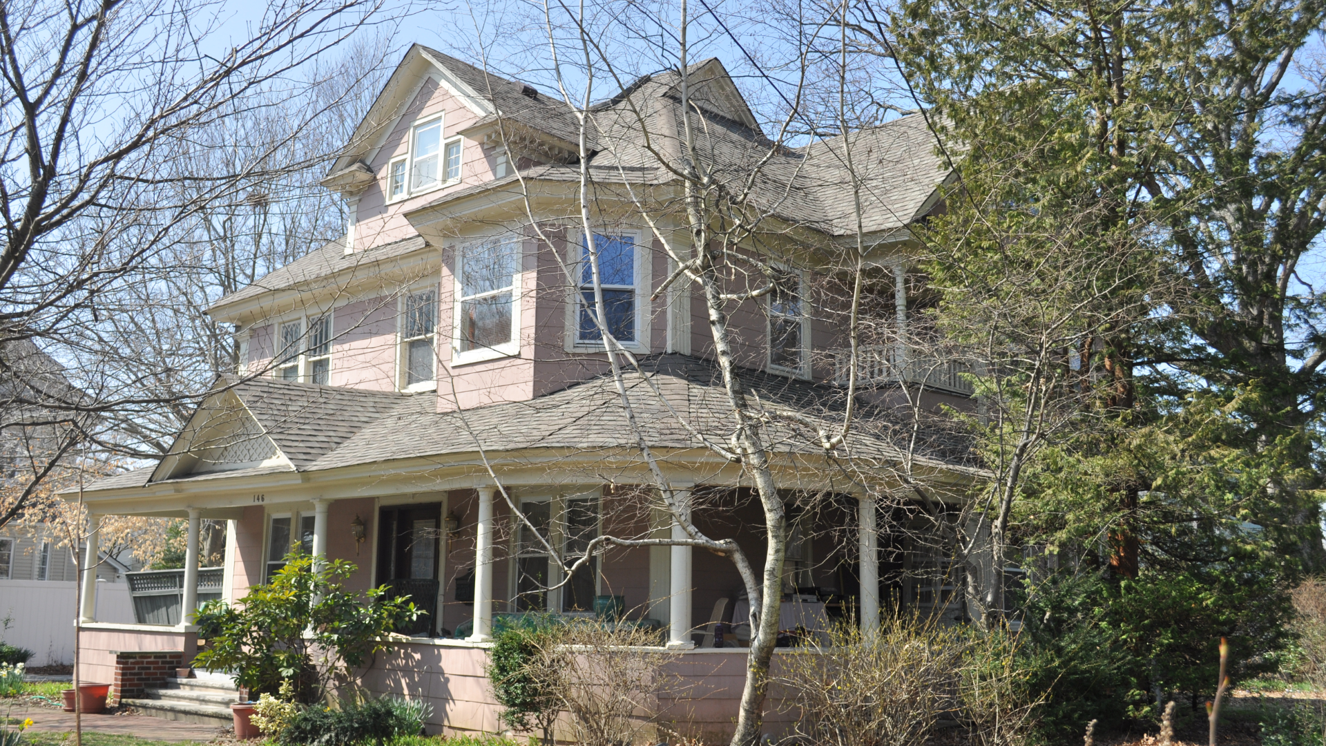 White farmhouse with gray roof and black garage doors.