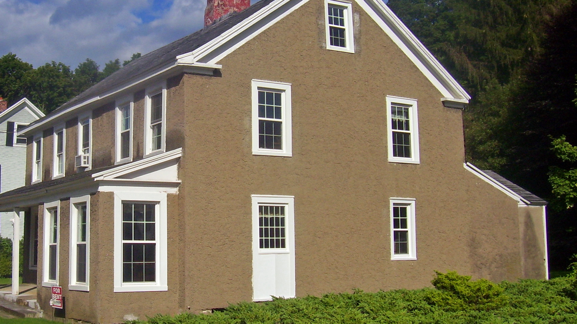 Blue house with stone columns, wooden door, and stone walkway leading to the front porch.
